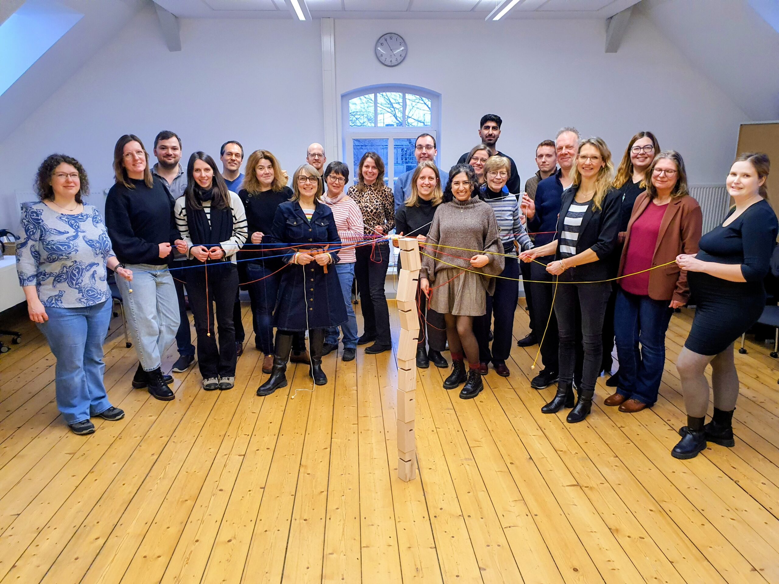 Die Teilnehmenden des 4. DTN-Workshops stehen in einem Halbkreis um einen Turm von auf einander gestapelten großen Bauklötzen.