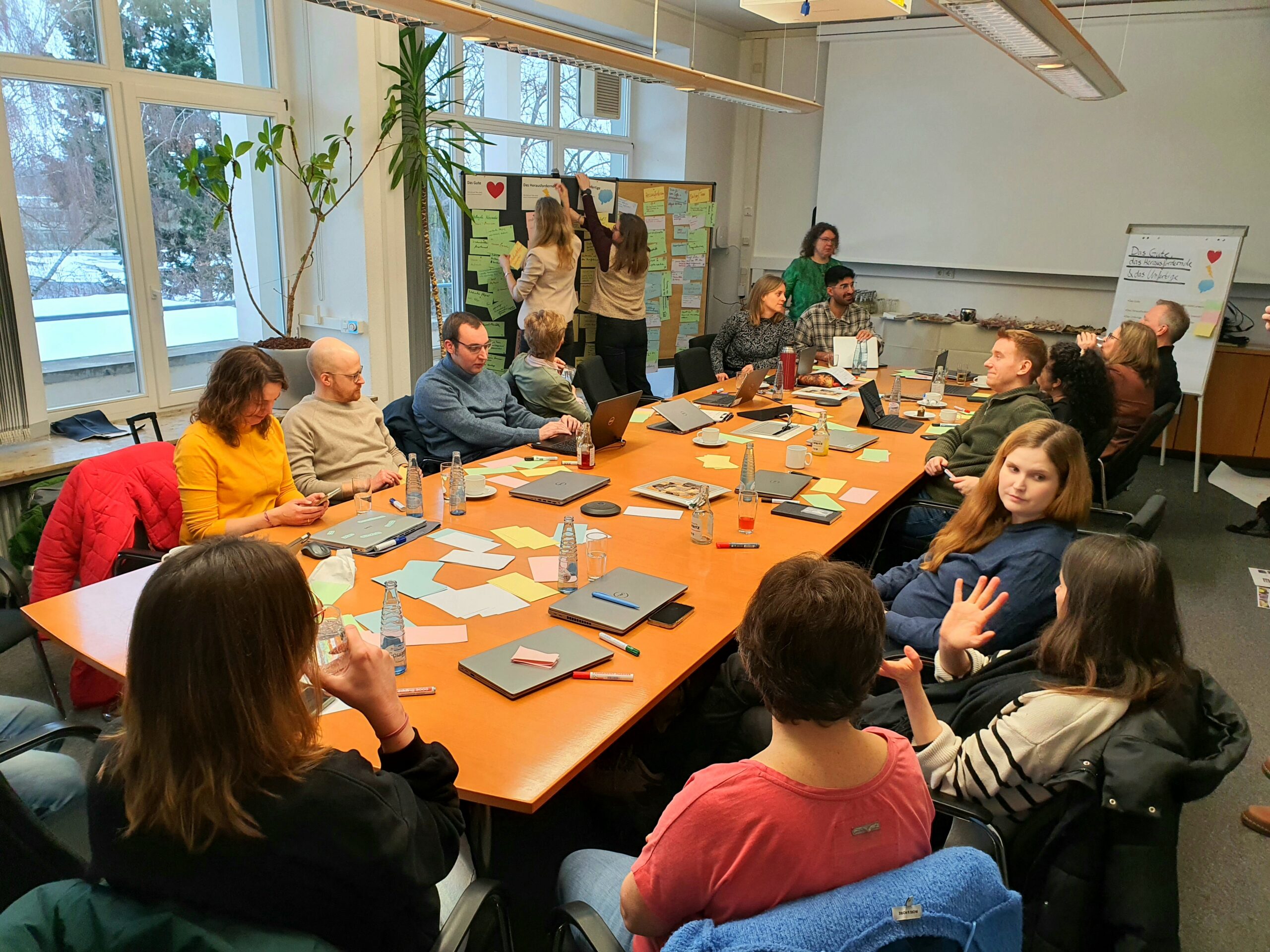 Die Teilnehmenden des 4. DTN-Workshops sitzen an einem Tisch und sind in Gespräche vertieft.